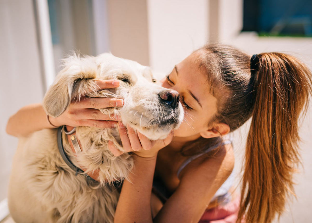 young girl kissing senior dog's face