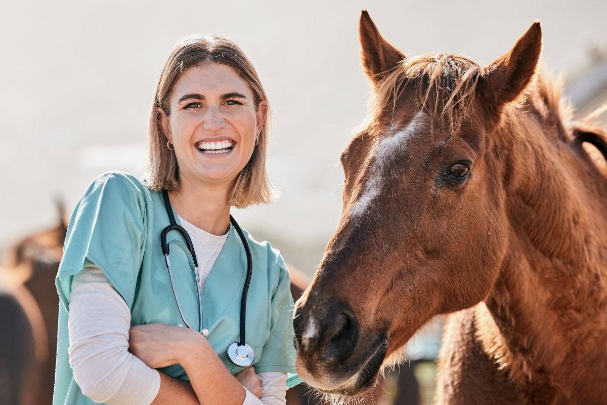 young veterinarian smiling next to horse